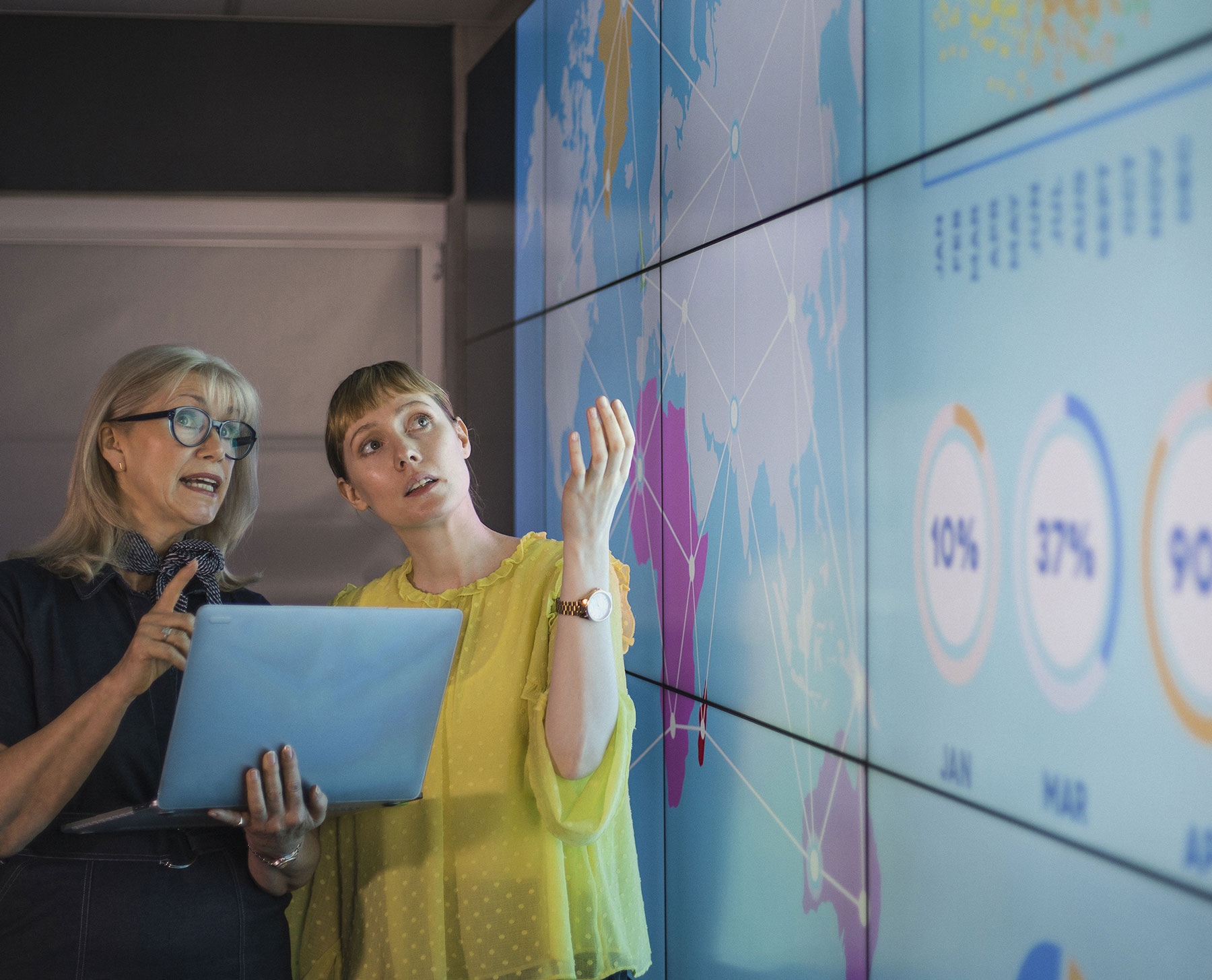 Businesswomen Discussing Ideas Against an Information Wall