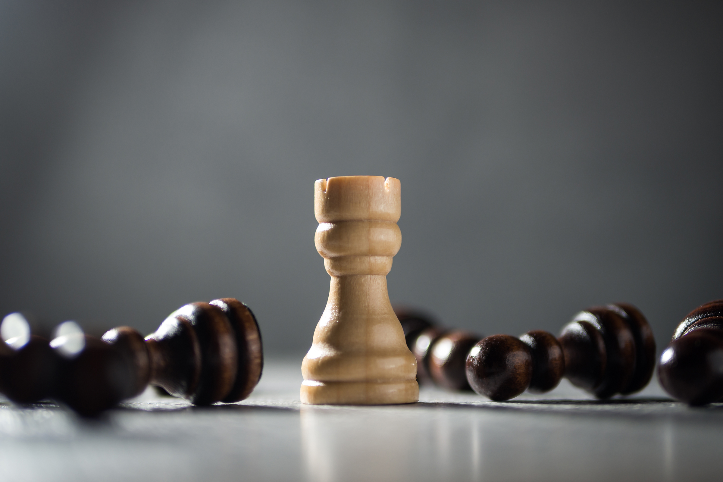 Resilience, perseverance and victory concept. Rook standing among fallen pawns.